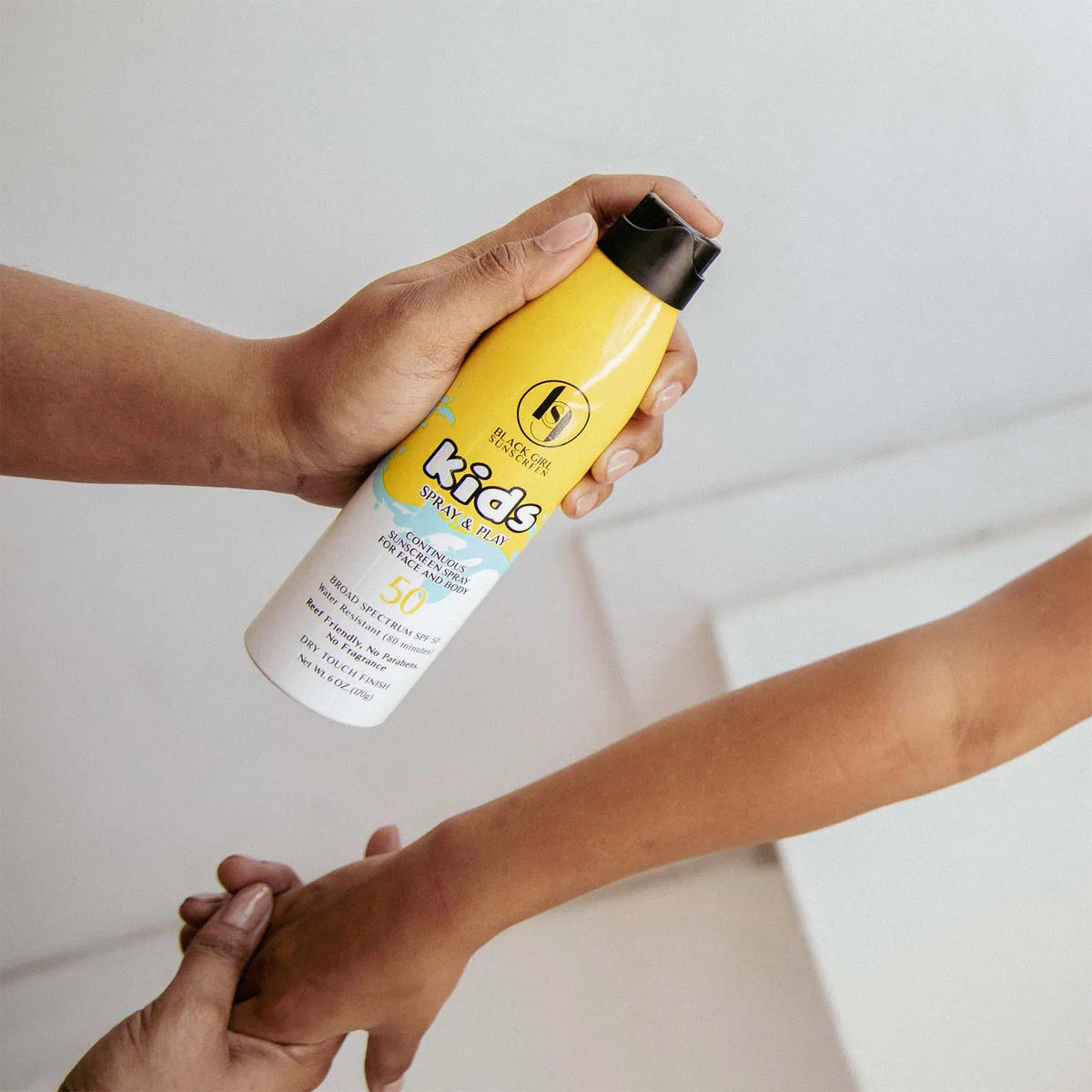 Kids Spray &amp; Play SPF 50 Continuous Sunscreen for Face and Body spraying on child&#39;s arm